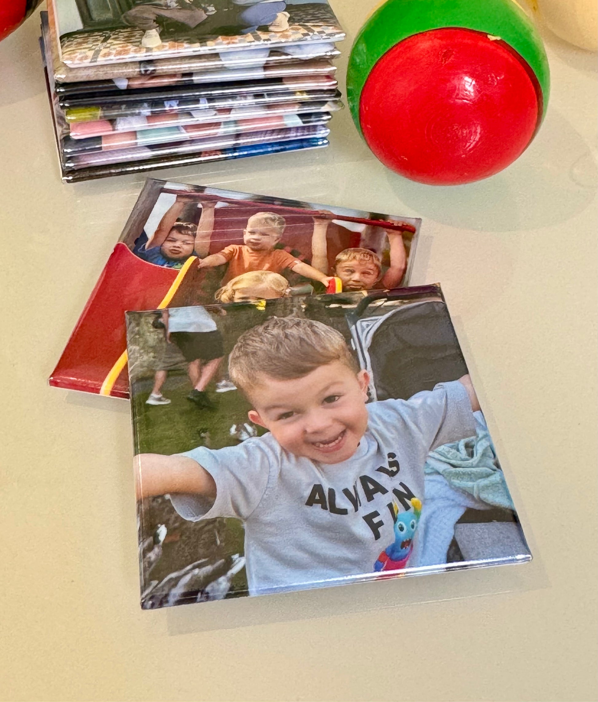 Stack of photo books with a child's picture on a table with colorful balls.